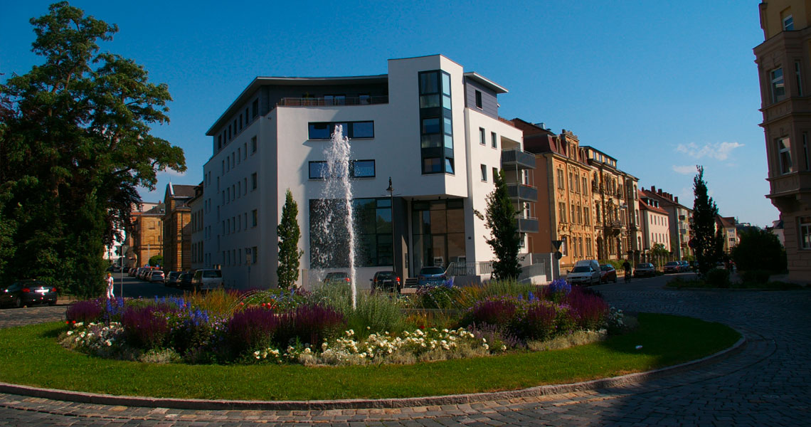 Wilhelmsplatz in Bayreuth mit Springbrunnen, dahinter das Gebaeude mit Architekturbuero