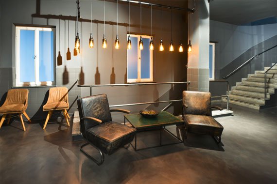 Lounge-Sessel in einem Raum mit industriellem Look und Haengeleuchten